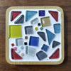 A square coaster with a bamboo tray, colorful tesserae, and white grout.