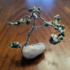 A wire sculpture tree with moss agate leaves on a quartz stone