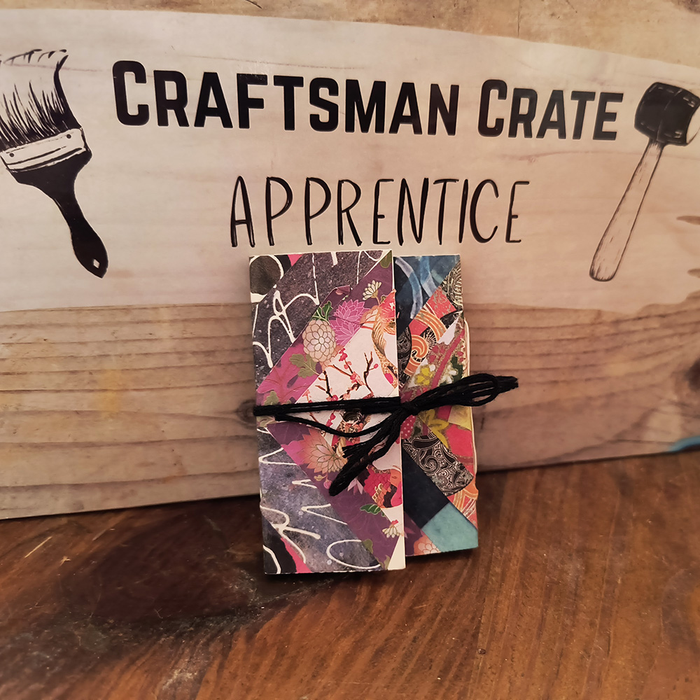 Mini Book against Apprentice Box 1000x1000 Mini Book with Patchwork Origami Cover leaning against an Apprentice box on a wooden table